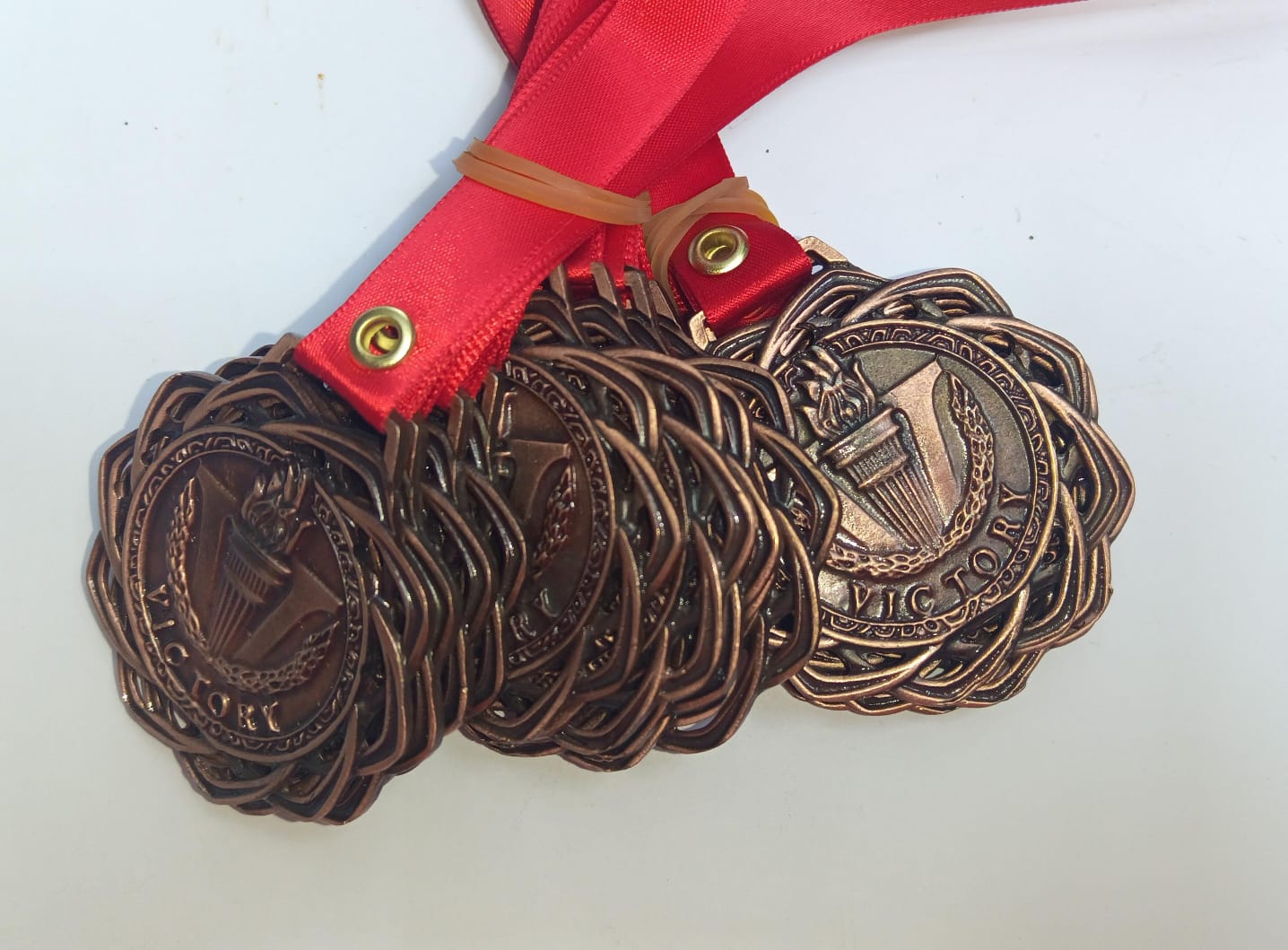 Medallas bronce con diseño trenzado y listón rojo